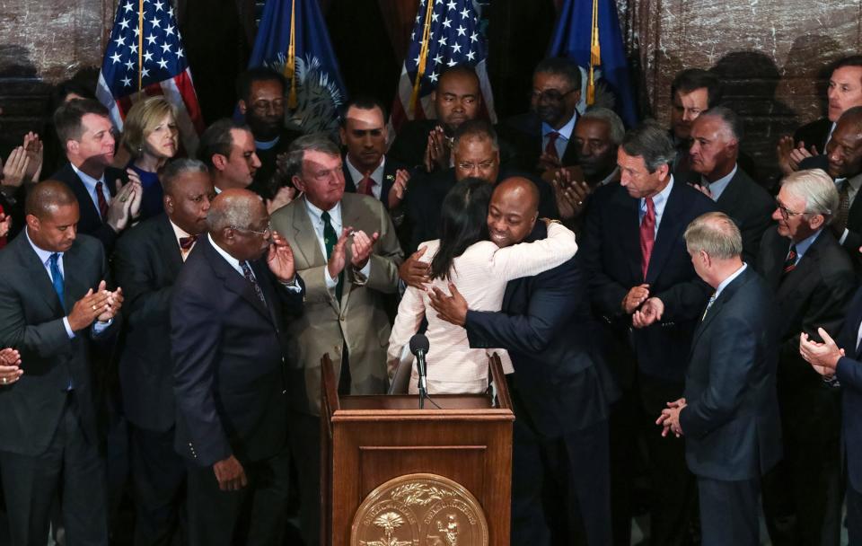 South Carolina Gov. Nikki Haley, center, embraces U.S. Sen. Tim Scott during a news conference in the South Carolina State House on Monday in Columbia, S.C. Haley said that the Confederate flag should come down from the grounds of the state Capitol, reversing her position on the divisive symbol amid growing calls for it to be removed.