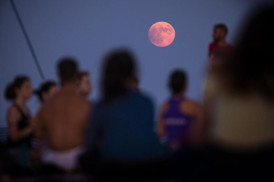 People take part in a yoga class in front of the partial lunar eclipse in Barcelona (AP)