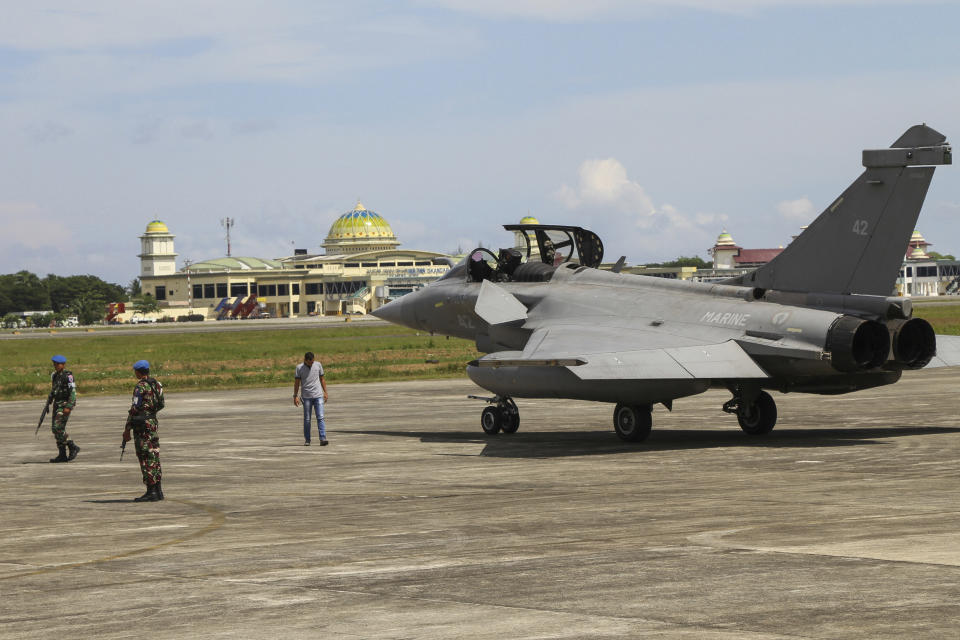 Indonesian military personnel stand guard near one of seven French Navy Rafale jet fighters parked on the tarmac at Sultan Iskandar Muda Air Base in Aceh Besar, Indonesia, Sunday, May 19, 2019. Poor weather has forced the seven fighters from French Navy aircraft carrier Charles de Gaulle taking part in a training exercise to make emergency landings in northern Indonesia. (AP Photo/Khalis Surry)