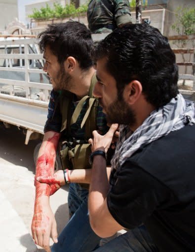 An injured Free Syrian Army fighter is taken to a hospital in Qusayr, on May 13, after heavy fighting broke out. Syrian troops have attacked a central rebel bastion, with dozens reportedly killed across the country, as the EU slaps fresh sanctions on Damascus