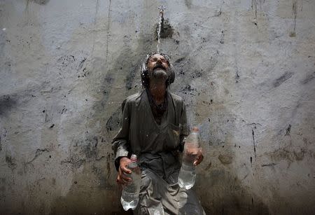 A man cools off from a public tap after filling bottles during intense hot weather in Karachi, Pakistan, June 23, 2015. REUTERS/Akhtar Soomro