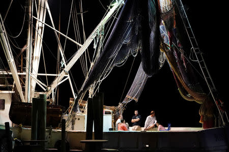 Fishermen sit on the back deck of their boat with the lights on following Hurricane Michael in Apalachicola, Florida, U.S., October 13, 2018. REUTERS/Carlo Allegri