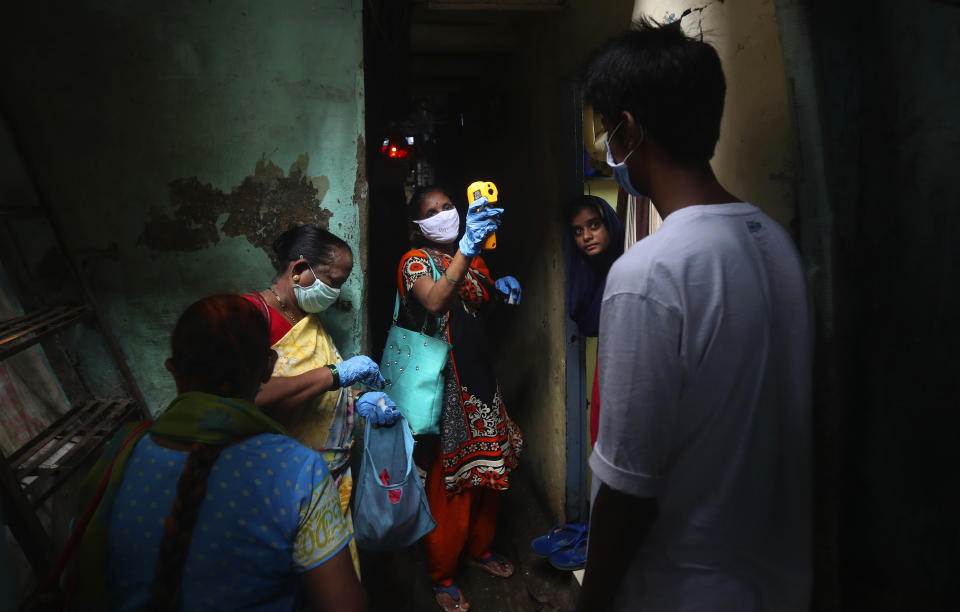 FILE - In this Monday, July 6, 2020, file photo, a health worker screens people for COVID-19 symptoms at Dharavi, one of Asia's biggest slums, in Mumbai, India. In just three weeks, India's confirmed cases shot up from the world’s sixth to the third-worst hit country by the coronavirus pandemic, according to a tally by Johns Hopkins University. India's fragile health system was bolstered during stringent monthslong lockdown but could still be overwhelmed by an exponential rise in infections. (AP Photo/Rafiq Maqbool, File)