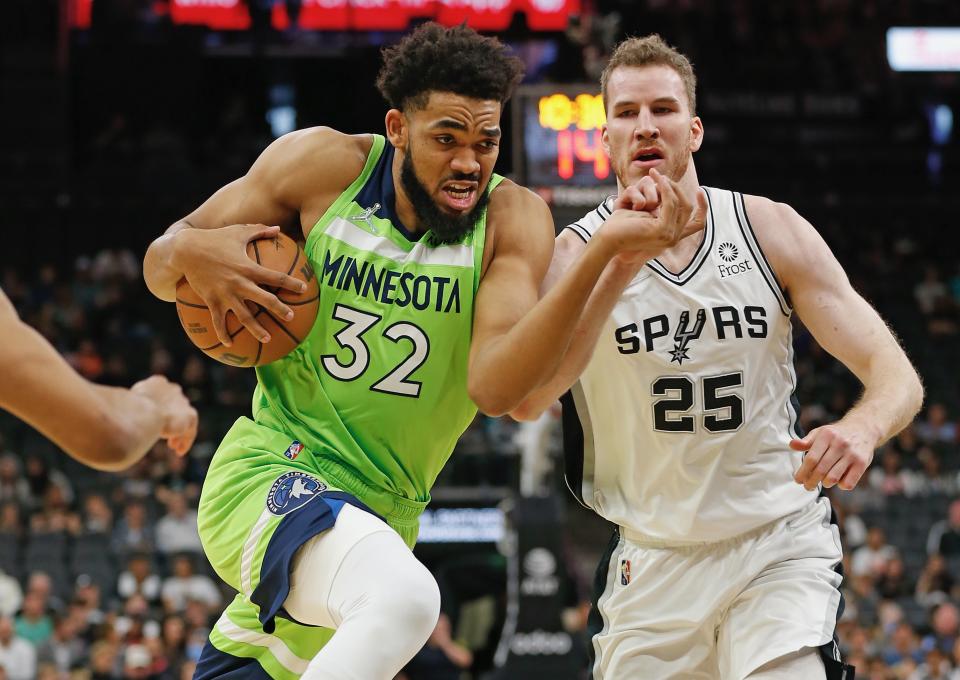 SAN ANTONIO, TX - MARCH 14:  Karl-Anthony Towns #32 of the Minnesota Timberwolves drives past Jakob Poeltl #25 of the San Antonio Spurs in the first half at AT&T Center on March 14,  2022 in San Antonio, Texas. NOTE TO USER: User expressly acknowledges and agrees that, by downloading and or using this photograph, User is consenting to terms and conditions of the Getty Images License Agreement. (Photo by Ronald Cortes/Getty Images)