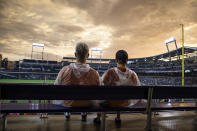 Two Texas fans watch the sun come out as the weather clears for start of the baseball game between Texas and Virginia in the College World Series Thursday, June 24, 2021, at TD Ameritrade Park in Omaha, Neb. (AP Photo/John Peterson)