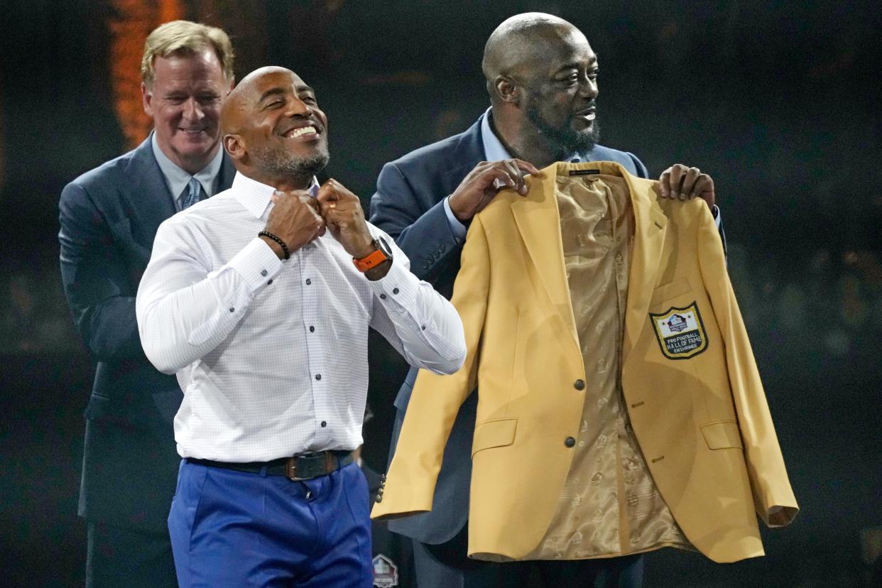 Rondé Barber, front left, a member of the Pro Football Hall of Fame Class of 2023, receives his gold jacket from Pittsburgh Steelers coach Mike Tomlin on Friday in Canton.