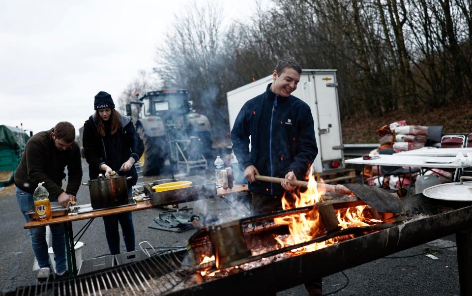 A farmer of the CR47 union lights a fire and others prepare food on the A16 highway next to the exit of Beauvais North