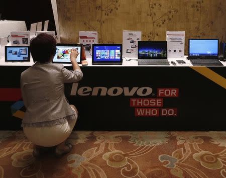 A woman tries a Lenovo tablet on display during a news conference announcing the company's annual results in Hong Kong May 21, 2014.