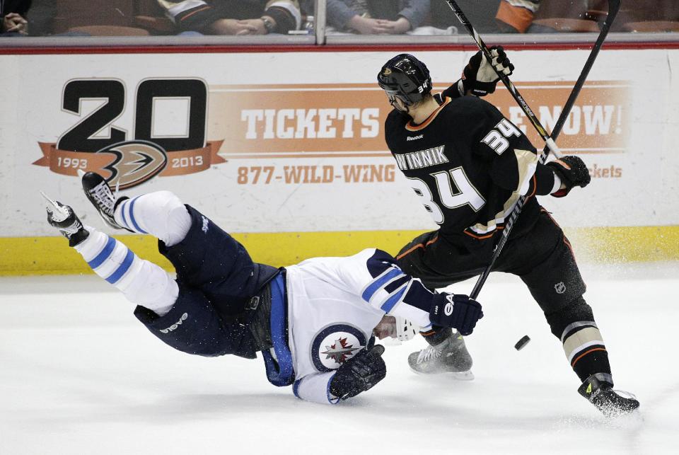 Winnipeg Jets' Andrew Ladd, left, falls to the ice while fighting for the puck with Anaheim Ducks' Daniel Winnik during the first period of an NHL hockey game, Tuesday, Jan. 21, 2014, in Anaheim, Calif. (AP Photo/Jae C. Hong)