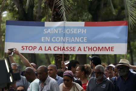 Supporters of Francois Fillon, former French prime minister, member of The Republicans political party and 2017 presidential candidate of the French centre-right, hold a banner as he gives a television interview in Saint-Paul as he campaigns on the French Indian Ocean island of the Reunion, February 12, 2017. Banner reads, "Stop the Manhunt". REUTERS/Laurent Capmas