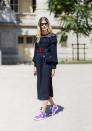 <p>Heilbrunner wears a navy lace pleated dress, purple sneakers, and black Wayfarers. (Photo: Getty) </p>