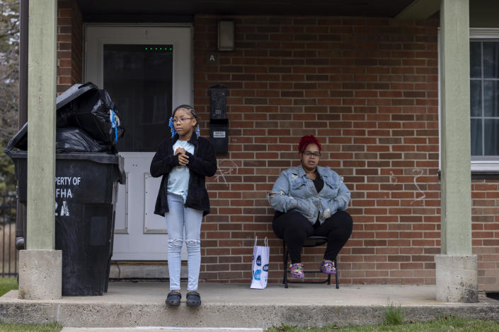 Ke'Arrah Jessie, 9, stands on the porch with her mom, Ashley Martin, as she plays outside with her brothers in Niagara Falls, N.Y., on Monday, April 3, 2023. (AP Photo/Lauren Petracca)