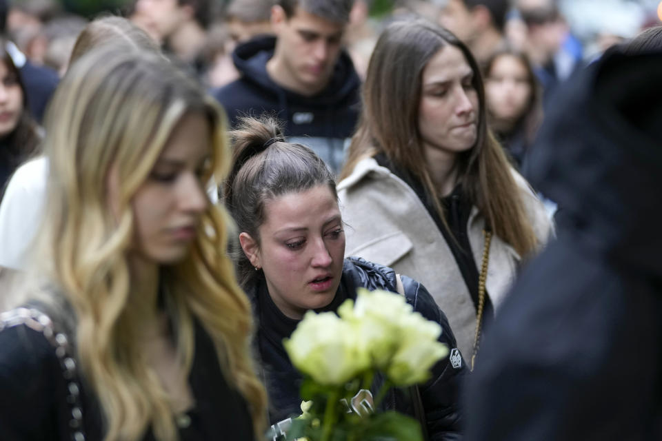 People bring flowers for the victims in front of the Vladimir Ribnikar school in Belgrade, Serbia, Thursday, May 4, 2023. A 13-year-old who opened fire Wednesday at his school in Serbia's capital killed eight fellow students and a guard before calling the police and being arrested. Six children and a teacher were also hospitalized. (AP Photo/Darko Vojinovic)