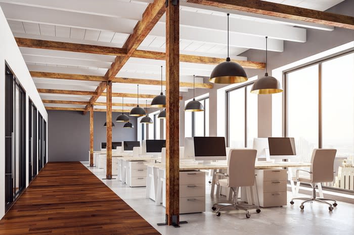 An empty office with exposed wood beams and modern furniture.