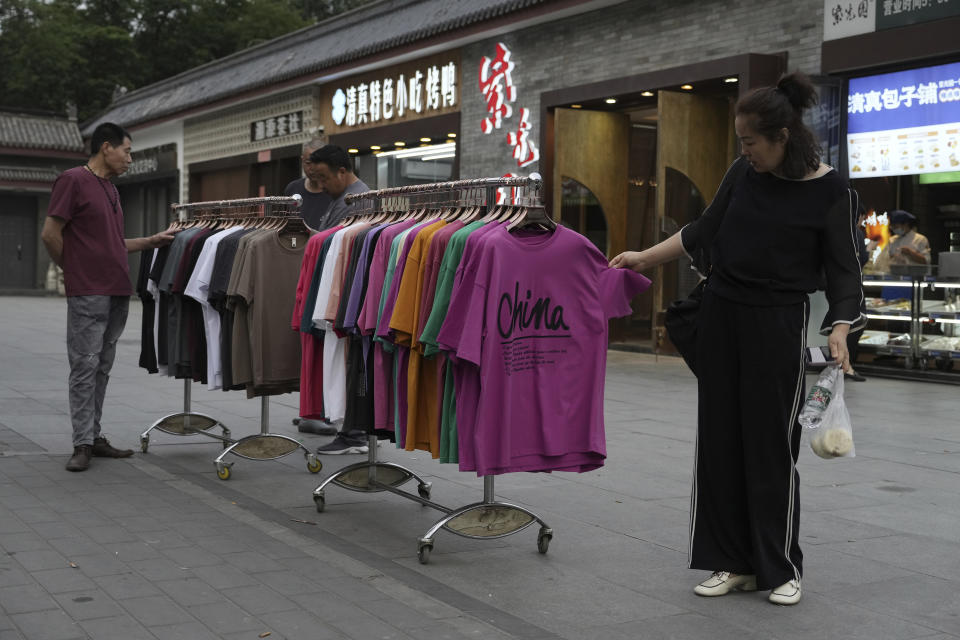 A woman looks at apparel on sale on the street in Beijing, Monday, May 29, 2023. China's factory activity decelerated in May, a survey showed Wednesday, adding to signs its economic rebound after the end of anti-virus controls is slowing. (AP Photo/Ng Han Guan)