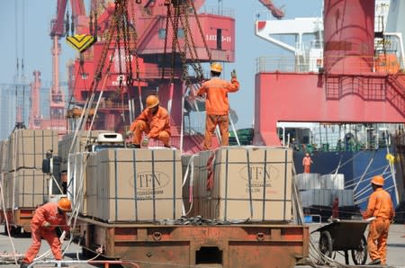 FILE PHOTO: Workers load goods for export onto a crane at a port in Lianyungang