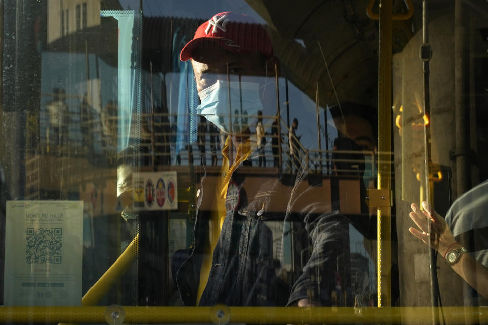 FILE - A bus attendant waits for passengers at a bus stop in metro Manila, Philippines on Sept. 8, 2022. Philippine President Ferdinand Marcos Jr. is extending a state of calamity declared by his predecessor more than two years ago to deal with continuing concerns over the coronavirus pandemic, an official said Monday, Sept. 12, 2022. (AP Photo/Aaron Favila, File)