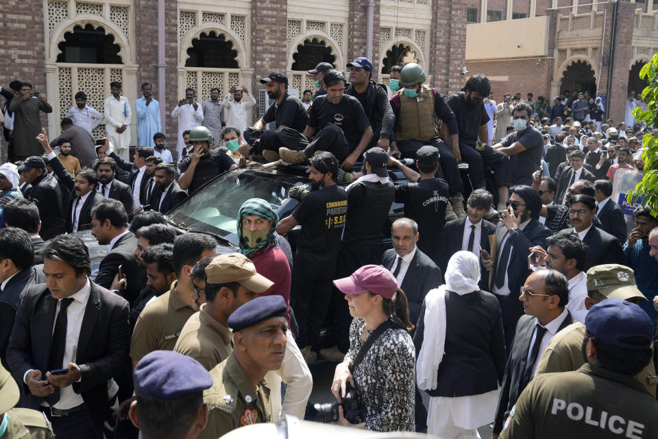 Security escort a vehicle carrying Pakistan's former Prime Minister Imran Khan and his wife Bushra Bibi after their court appearance, in Lahore, Pakistan, Monday, May 15, 2023. Thousands of Pakistani government supporters converged on the country's Supreme Court on Monday, in a rare challenge to the nation's judiciary. Protesters demanded the resignation of the chief justice over ordering the release of former Prime Minister Imran Khan. (AP Photo/K.M. Chaudary)