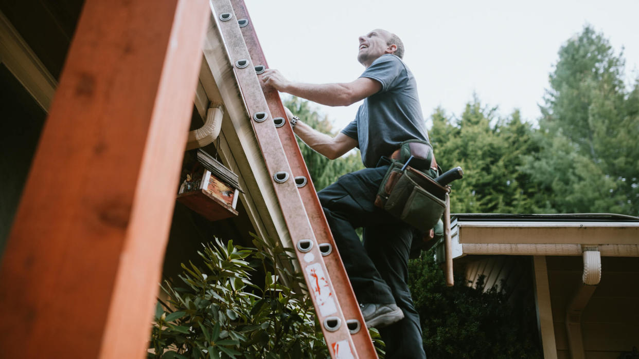 A roofer and crew work on putting in new roofing shingles.