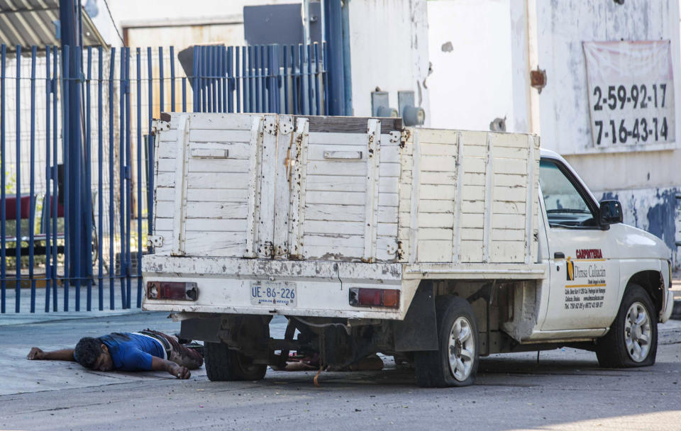The bullet riddled bodies of two men lie on the ground next to a vehicle, a day after a gun battle between gunmen and security forces in Culiacan, Mexico, Friday Oct. 18, 2019. Mexican officials say eight people were killed in the battles in what is being described as a failed operation to detain the son of convicted Sinaloa cartel boss Joaquin "El Chapo" Guzman. (AP Photo/Augusto Zurita)