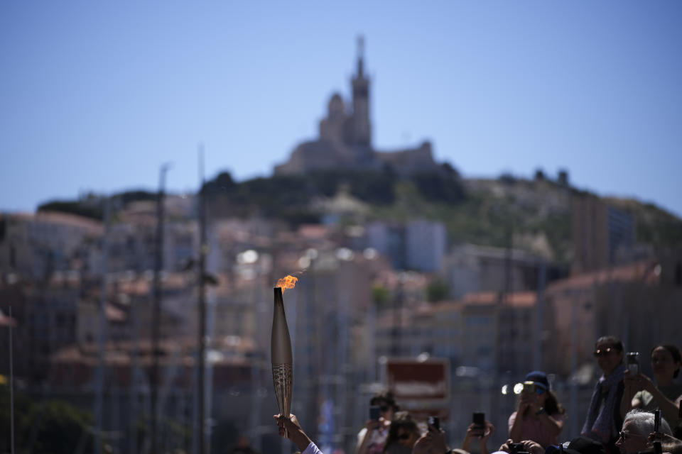 The Olympic torch is raised during the torch relay in Marseille, southern France, Thursday, May 9, 2024. Torchbearers are to carry the Olympic flame through the streets of France' s southern port city of Marseille, one day after it arrived on a majestic three-mast ship for the welcoming ceremony. (AP Photo/Daniel Cole)