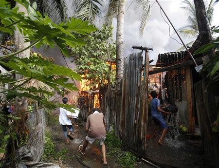 Residents attempt to extinguish the flames from burning houses, caused by a firefight between government soldiers and Muslim rebels from the Moro National Liberation Front (MNLF), in a residential district in Zamboanga city in southern Philippines September 12, 2013.REUTERS/Erik De Castro