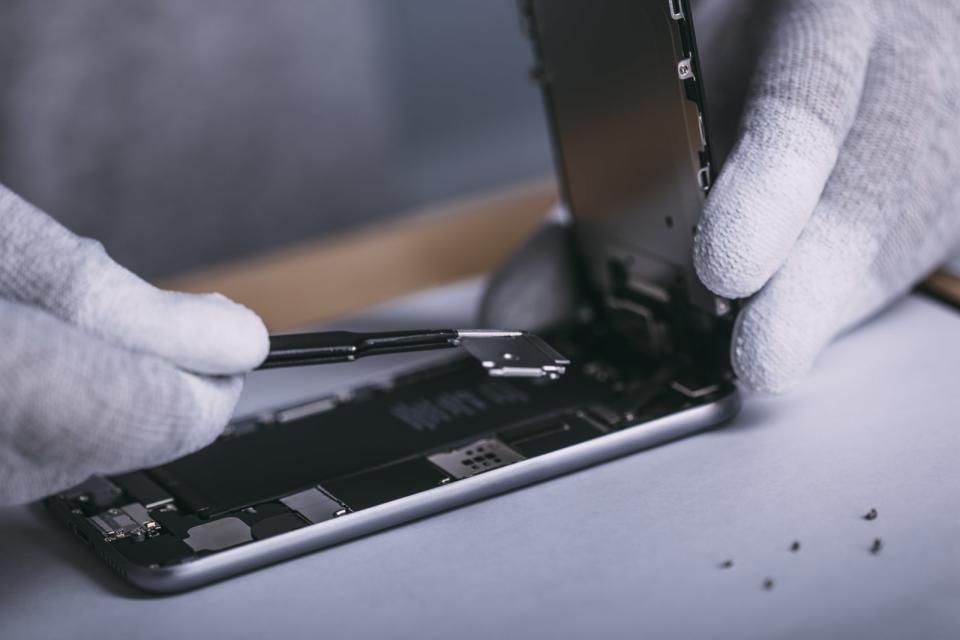 Detail image of male technician repairing smart phone at electronics store