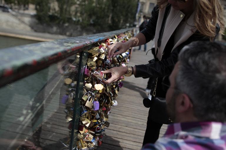 A couple locks a padlock on the "Pont des Arts" on May 29, 2015, in Paris