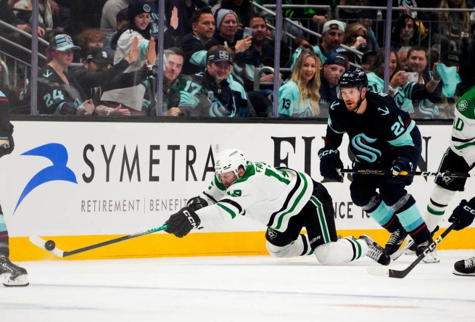 Dallas Stars center Radek Faksa (12) falls while trying to keep control of the puck against Seattle Kraken defenseman Jamie Oleksiak (24) during the second period of Game 3 of an NHL hockey Stanley Cup second-round playoff series Sunday, May 7, 2023, in Seattle. (AP Photo/Lindsey Wasson)