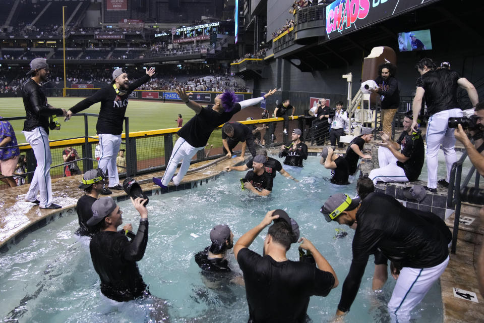 Arizona Diamondbacks left fielder Lourdes Gurriel Jr., center, falls into the pool after the Diamondbacks defeated the Los Angeles Dodgers 4-2 in Game 3 to win a baseball NL Division Series, Wednesday, Oct. 11, 2023, in Phoenix. (AP Photo/Rick Scuteri)