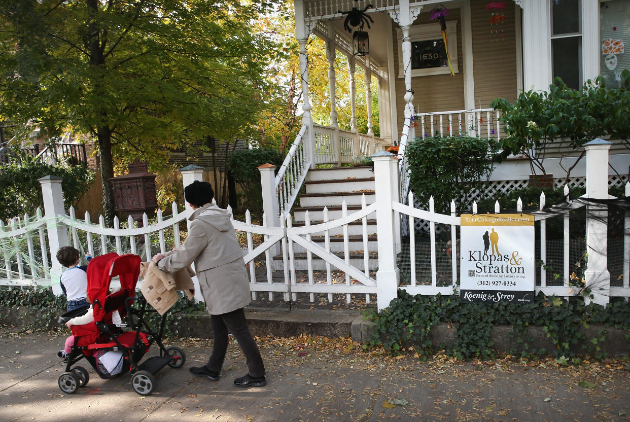 A person pushes a stroller past a home that is offered for sale in the Wicker Park neighborhood in Chicago. (Credit: Scott Olson, Getty Images)