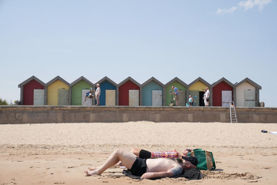 A couple sunbathe on Blyth beach, Northumberland, on the north east coast of England, Monday July 18, 2022. Britain’s first-ever extreme heat warning is in effect for large parts of England as authorities prepare for record high temperatures that are already disrupting travel, health care and schools. The “red” alert will last throughout Monday and Tuesday when temperatures may reach 40 degrees Celsius (104 Fahrenheit) for the first time, posing a risk of serious illness and even death among healthy people, according to the U.K. Met Office, the country’s weather service. (Owen Humphreys/PA via AP)