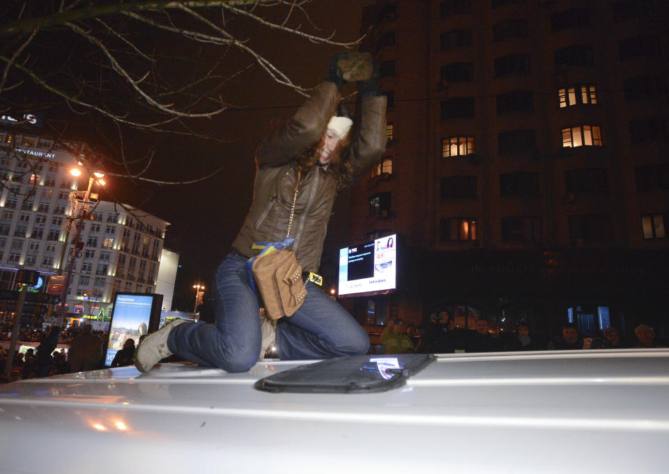 FILE - In this Nov. 25, 2013 file photo, Ukrainian journalist Tetyana Chernovil beats the roof of a police minivan with a stone during a pro-European Union rally in Kiev, Ukraine. Chernovil was tapped as head of an anti-corruption committee in the new government. Top figures in Ukraine's three-month protest are taking up powerful posts in the new Cabinet, underscoring the powerful and unpredictable force of the revolt. But while few doubt the leaders' resolve, the nominations have raised questions about their skills and expertise — especially given the enormous challenges the new government faces. (AP Photo/Andrew Kravchenko, File)