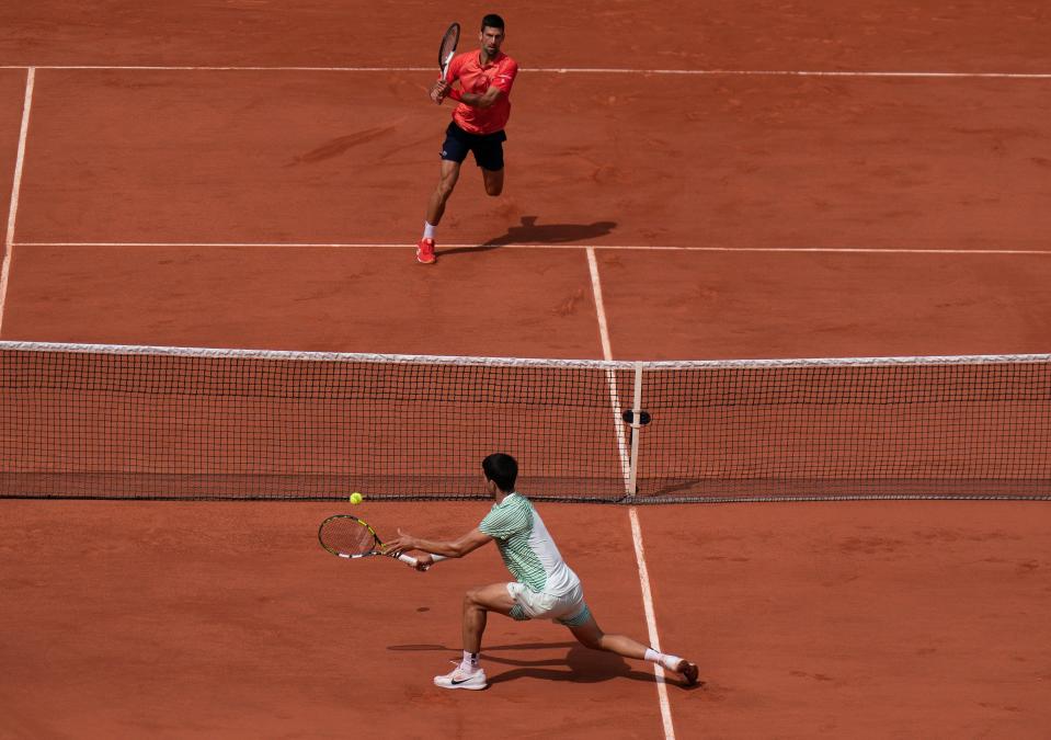 Carlos Alcaraz (bottom) returns a shot during his semifinal match against Novak Djokovic (top) during the semifinal match of the French Open.