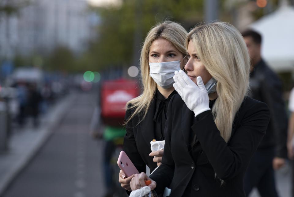 Two women wearing face masks against coronavirus as wait to cross the road in the center of in Moscow, Russia, Wednesday, Sept. 23, 2020. Russia confirmed over six and half thousand new Covid-19 cases Wednesday, bringing the country's official number of cases to 1,122,241 as the number of new infections across the country continues to rise. (AP Photo/Alexander Zemlianichenko)