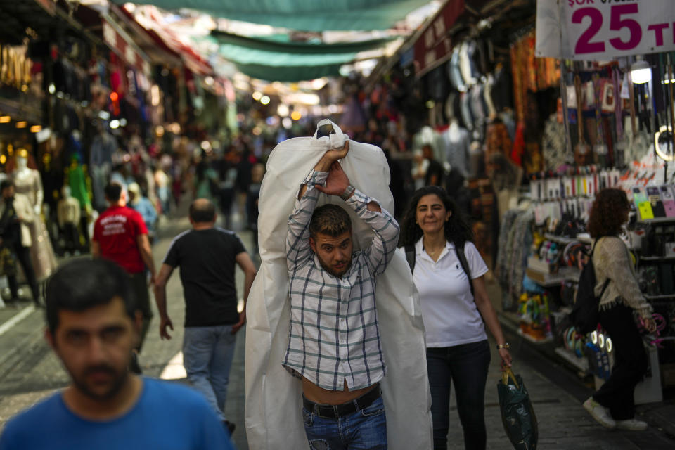 A man carries goods in a street market at Eminonu commercial area in Istanbul, Turkey, Wednesday, June 7, 2023. The Turkish lira tumbled to fresh record lows on Wednesday, extending its slide against the dollar since President Recep Tayyip Erdogan won a third presidential term in elections last month. (AP Photo/Francisco Seco)