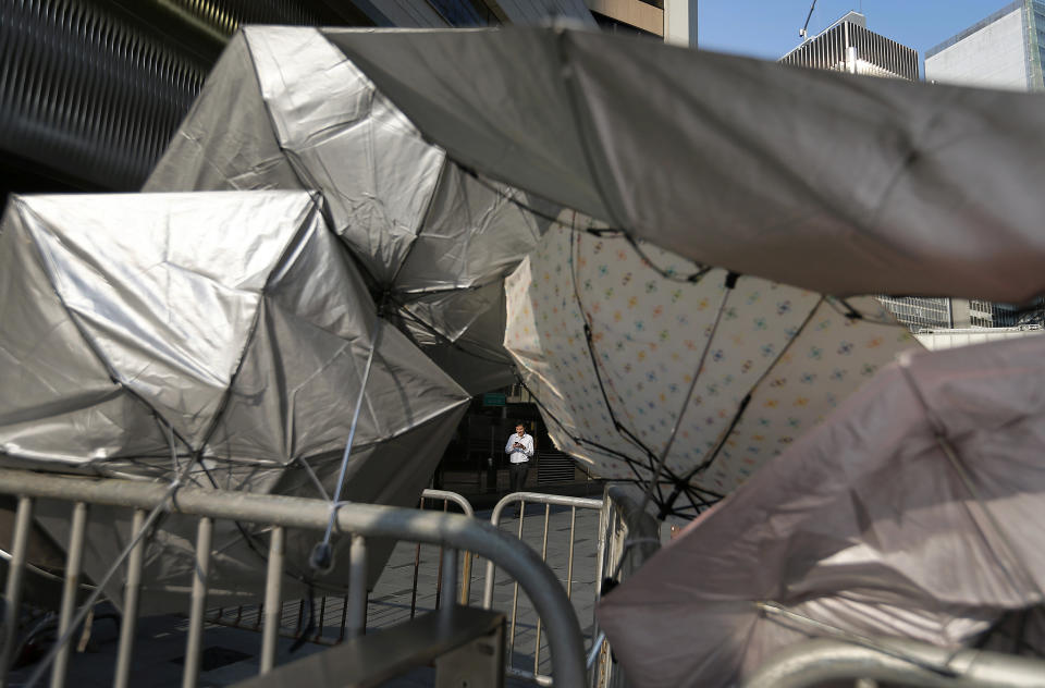 A man is framed by a barricade made of metal gates and umbrellas in the central financial district, Tuesday, Sept. 30, 2014, in Hong Kong. (AP Photo/Wong Maye-E)