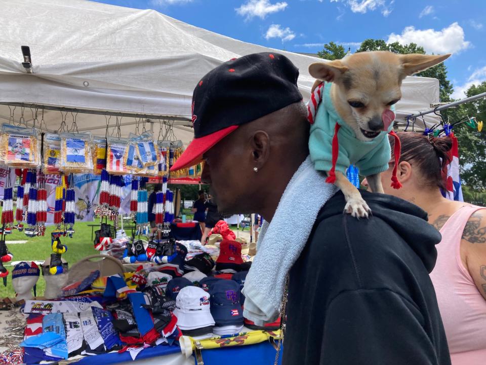 Max the dog sits on Walter Nadar's shoulders as he looks over the merchandise for sale at the Latin American Festival Saturday in Worcester.