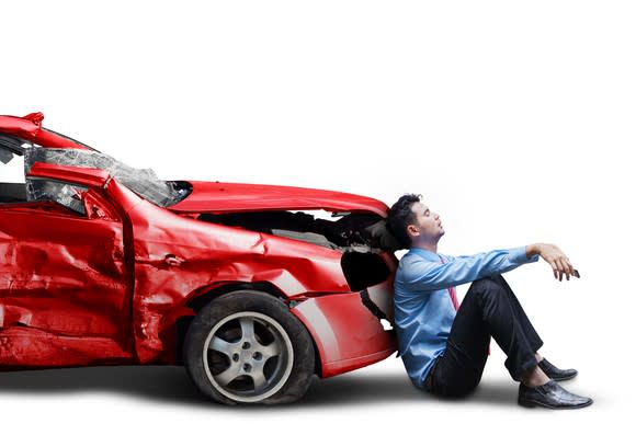 A person leaning against the hood of a crashed car