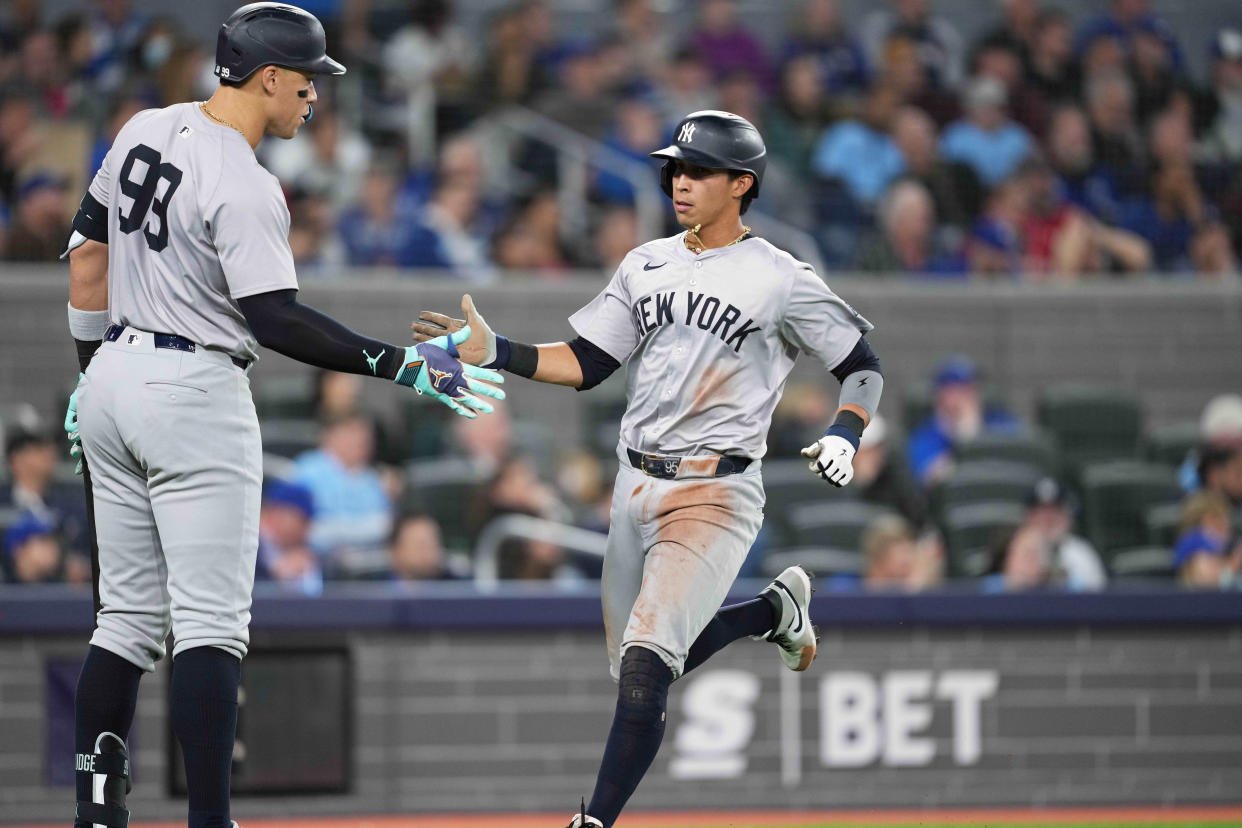 Apr 17, 2024; Toronto, Ontario, CAN; New York Yankees third base Oswaldo Cabrera (95) scores a run and celebrates with center fielder Aaron Judge (99) against the Toronto Blue Jays during the fifth inning at Rogers Centre.