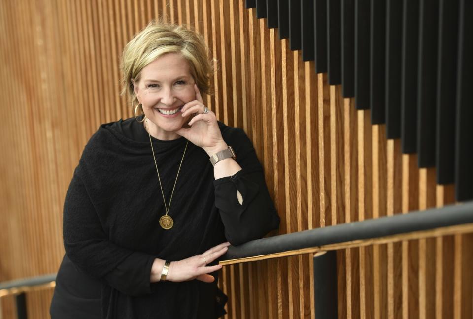 Brené Brown posing in a black shirt and gold necklace.