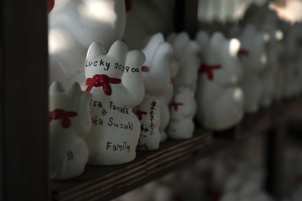 In this June 25, 2019, photo, messages are written on the back of beckoning cat figurines at Gotokuji Temple in Tokyo. According to a centuries-old legend provided by the temple, Gotokuji, a Buddhist temple located in the quiet neighborhood of Setagaya, is the birthplace of beckoning cats, the famous cat figurines that are widely believed to bring good luck and prosperity to home and businesses. Some visitors come just to snap a few photos, while others make a trip to the temple to pray and make wishes. (AP Photo/Jae C. Hong)