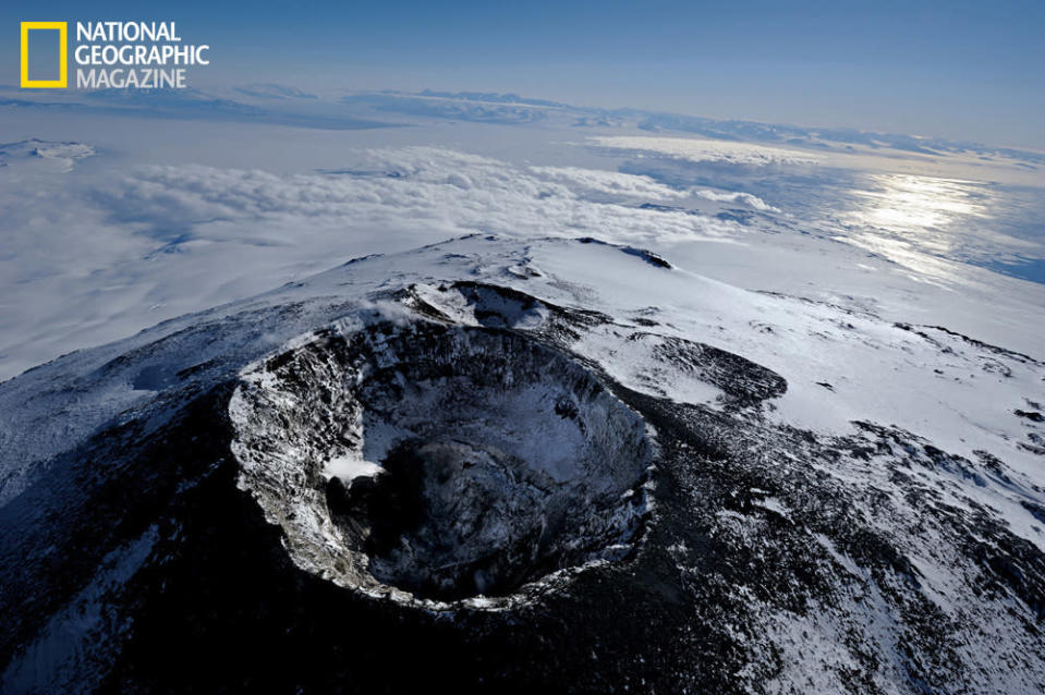 On a clear evening the main crater of the volcano is quiet, exuding just a few puffs of steam. Abutting it is another crater, now extinct. Beyond, a dreamscape of sea ice and ocean stretches to the mountains and dry valleys of the Antarctic mainland. (photo © Carsten Peter/National Geographic)