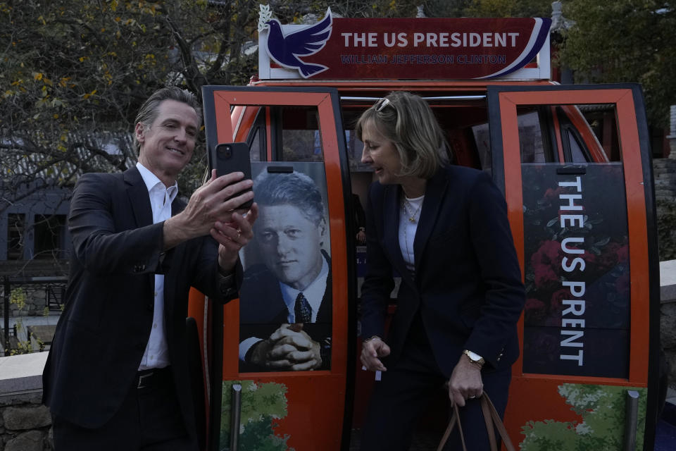 California Gov. Gavin Newsom, left, takes a selfie with a commemorative cable car carriage featuring former U.S. President Bill Clinton during a visit to the Mutianyu Great Wall on the outskirts of Beijing, Thursday, Oct. 26, 2023. Newsom is on a weeklong tour of China to push for climate cooperation. (AP Photo/Ng Han Guan)