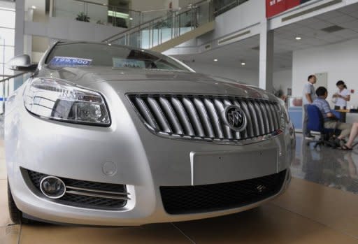 Customers stand next to a new Buick sedan displayed at a General Motors dealership in Beijing 2009. China said Thursday it will "withdraw support" for foreign investment in auto manufacturing to encourage domestic industry in the world's largest car market