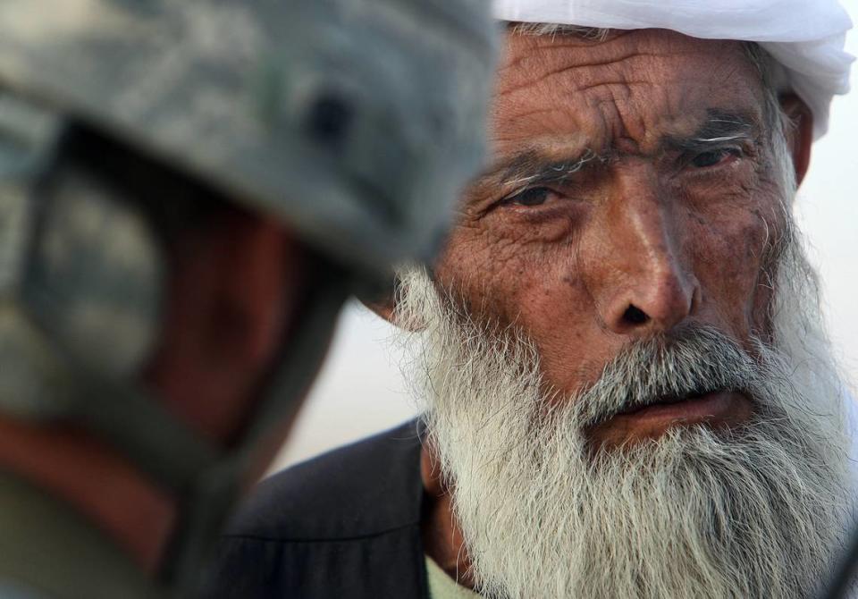 An elderly man eyes Lt. Hans Beutel of Huntersville, North Carolina, as the pair talk via an interpreter at a checkpoint near Kolk, Afghanistan on November 20, 2009.