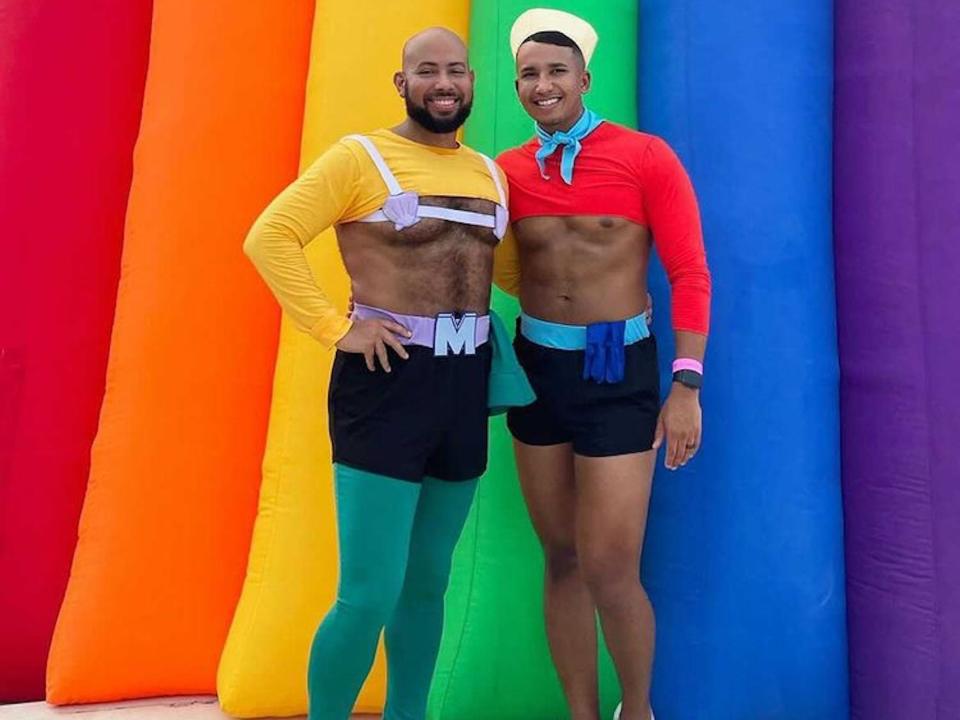 A man dressed as Mermaid Man poses in front of a rainbow backdrop next to a man dressed as Barnacle Boy from "Spongebob Squarepants."