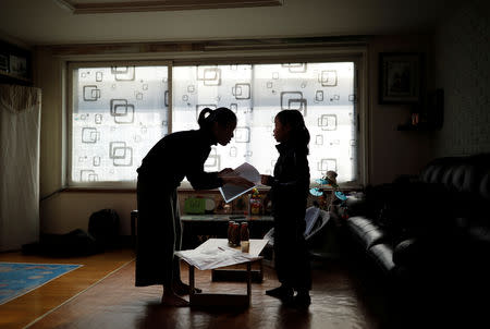 Kim Mi-sung checks her daughter's homework before leaving for school, at their home in Seoul, South Korea, December 19, 2018. REUTERS/Kim Hong-Ji