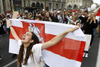 A woman reacts as she marches holding an old Belarusian national flag in the center of Minsk, Belarus, Friday, Aug. 14, 2020. Some thousands of people have flooded the cnetre of the Belarus capital, Minsk, in a show of anger over a brutal police crackdown this week on peaceful protesters that followed a disputed election. (AP Photo/Sergei Grits)