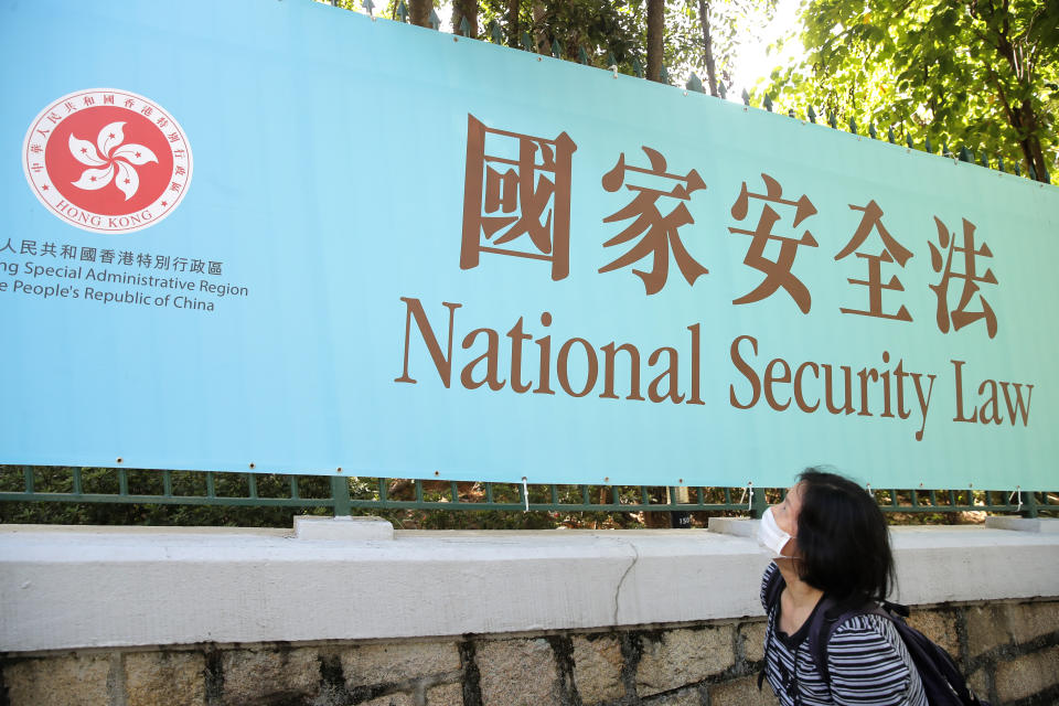 A woman walks past a promotional banner of the national security law for Hong Kong, in Hong Kong, Tuesday, June 30, 2020. China has approved a contentious law that would allow authorities to crack down on subversive and secessionist activity in Hong Kong, sparking fears that it would be used to curb opposition voices in the semi-autonomous territory. (AP Photo/Kin Cheung)